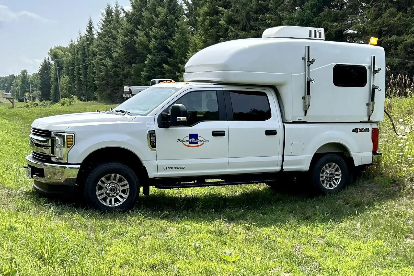 A white truck with an enclosed camper on the back.